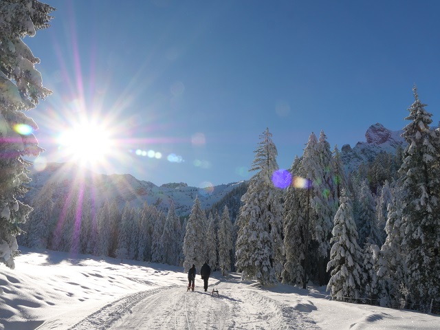 Winterwanderweg in den Bergen mit Sonne und Schnee